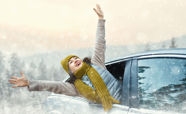 Excited woman arms extended out of car on snowy day