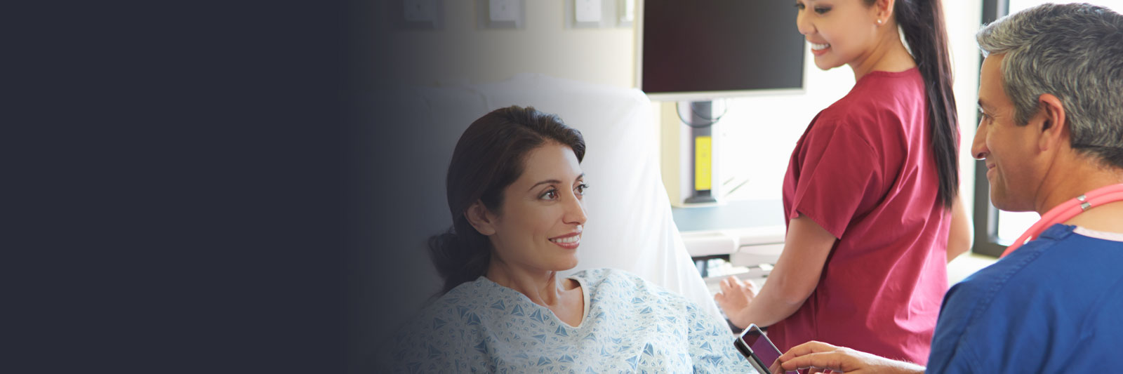 Smiling woman in a hospital bed talking with medical professionals during her care